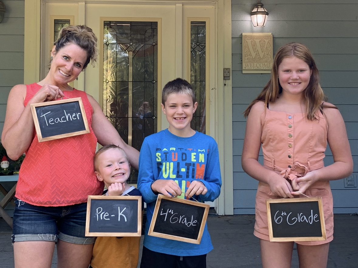 Sarah with her kids holding a Teacher sign